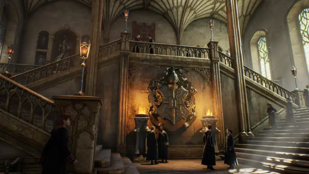 El salón principal de Hogwarts llena el espacio, los estudiantes descienden por las escaleras dobles, el gran escudo de armas de la escuela está iluminado por dos luces en pedestales.